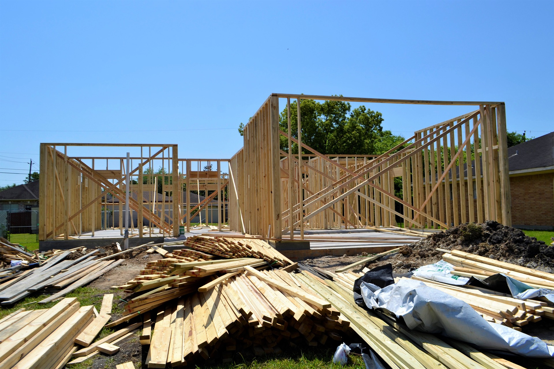 A home construction site with piles of lumber and walls already framed up.