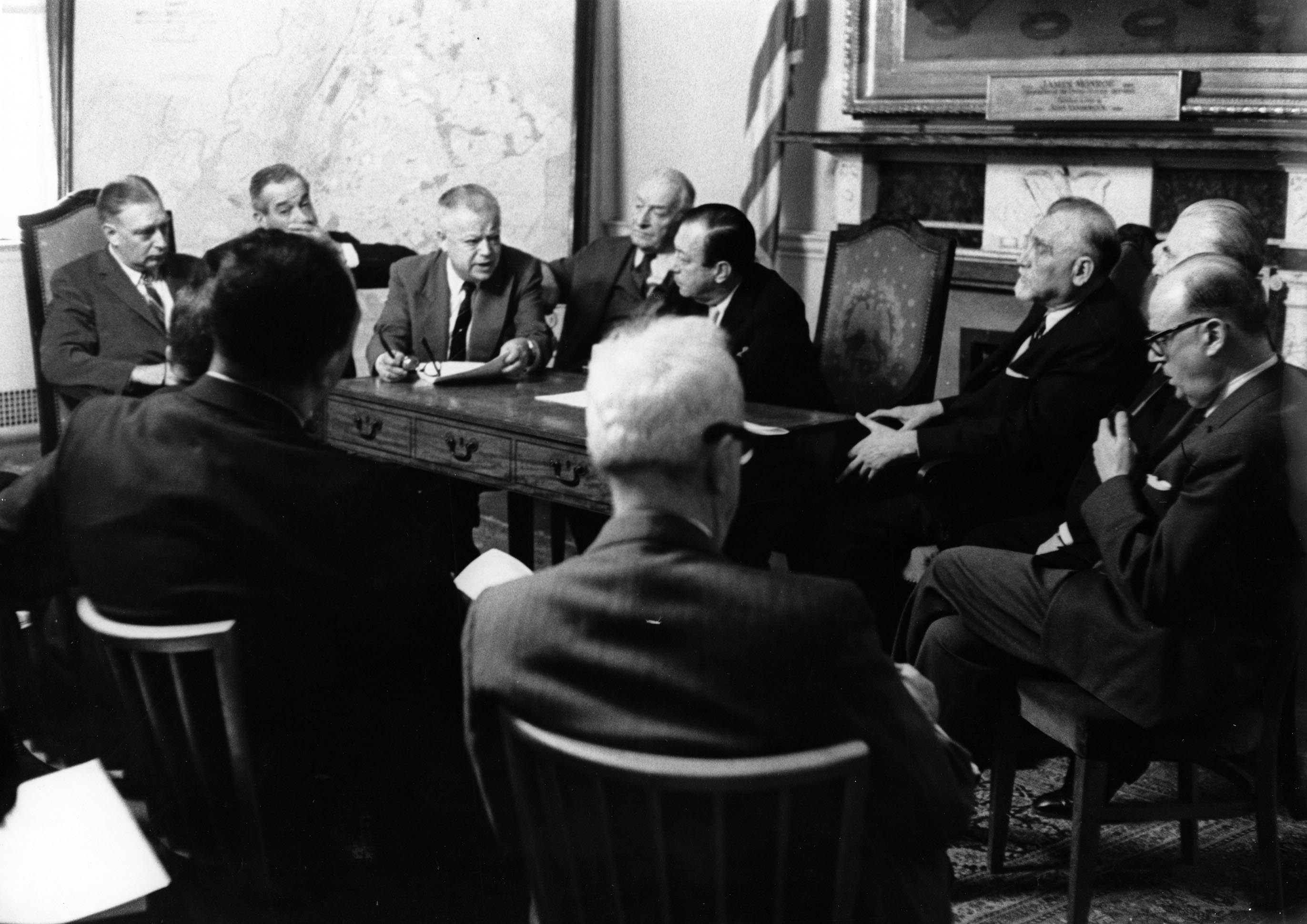 A vintage 1950s black and white photo of ten white men around a committee table.